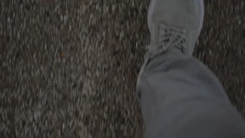 A top-down, motion-blurred view of a person wearing a light grey sneaker whil 動画素材 345020241