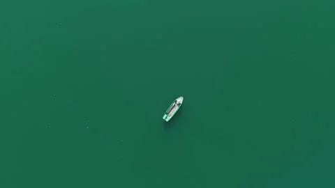 Top Down Orbiting Ascending Shot of a Boat With a Person in It on a Green River 库存影片 250339006