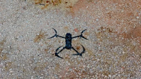 Top Down Overhead Shot of Quadcopter Drone Shadow on Gravel Road Stock-Footage 345685781