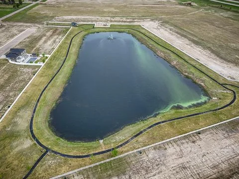 Top-down perspective captures a pond with dark center and green edges Stock Photos