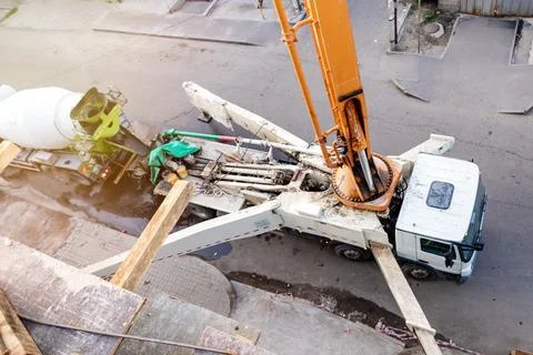 Top-Down Perspective: Concrete Pump Truck Transfers Mixer Truck Load for Floor Stock Photos