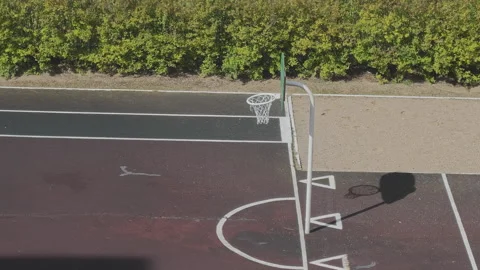 Top down perspective of an outdoor basketball hoop and court. Sunlight casting Stock Footage 345601657