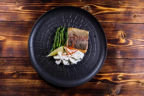 A top-down perspective of a skillfully plated fish fillet served with green b Stock Photos