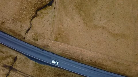 Top-down perspective of traffic on an asphalt road surrounded by mossy fields in Stockbeeldmateriaal 333702144