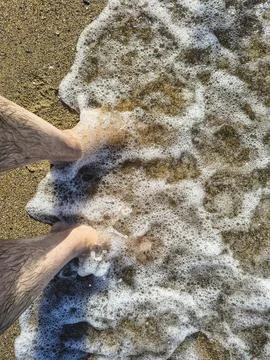 Top-down perspectives of human bare feet standing on wet sand and multiple fo Fotos Stock