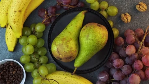 Top down rotating pears on brown plate with grapes bananas coffee beans and.. Stock Footage 320029178