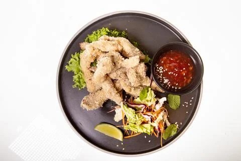 Top-down shot of battered and fried pieces of food on a black plate. This pla Fotos de archivo