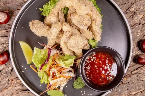 Top-down shot of battered and fried pieces of food on a black plate. This pla Stock Photos