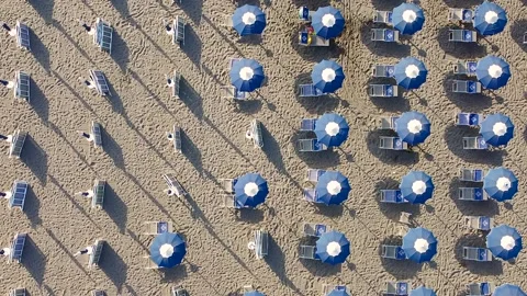 Top down shot of beach, showing blue umbrellas in empty bath house Video stock 137863920