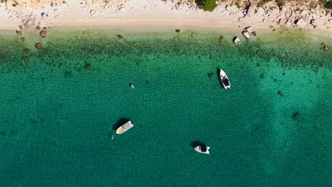 Top-down shot capturing the crystal-clear waters, vibrant coastline, and small Stock Footage 317771664