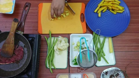 Top-down shot of chopping fresh baby corn into small pieces for steak side dish Stock Footage 345376712
