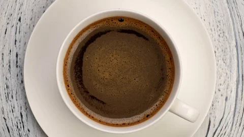 Top down shot of coffee foam swirls in white cup with coffee. Old wooden Video stock 120383979