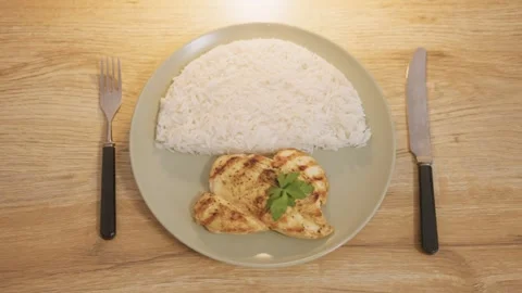 Top-down shot of grilled chicken breast with rice on a plate Vídeos de archivo 321193166