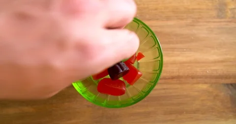 Top down shot of hands taking gummy candies out of a glass dish Stock Footage 113017516