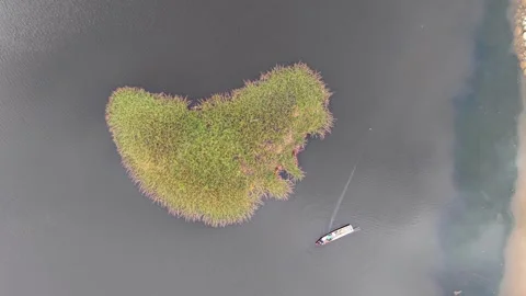 Top down shot of a heart shaped island surrounded by dark lake water Video stock 339857746