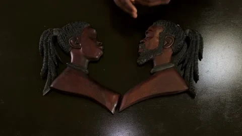 Top down shot of male and female African wooden masks with a hand reveal Stock Footage 199654298