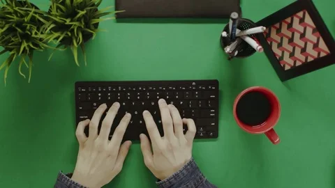 Top down shot of man typing on keyboard and taking a break to take a sip out of Stock Footage 81231382