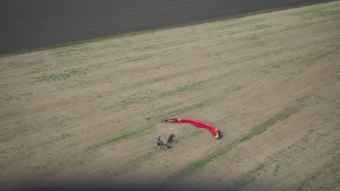 Top down shot of people preparing paraglider canopy beside motorized fan cart Stock Footage 317158838