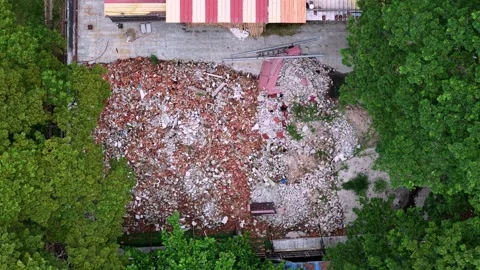 Top-down shot reveals rubble field next to partially standing structure Video stock 345835159