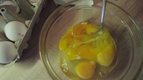 Top down shot of scrambling eggs in a glass bowl with a fork Video stock 237680430