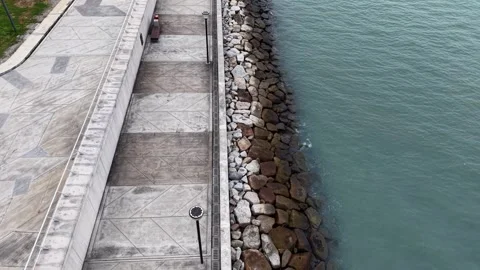 Top-down shot of seaside promenade bordered by rocky barrier Видео 345835181