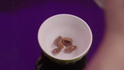 Top down shot of walnut being poured into a bowl Stock Footage 303463435