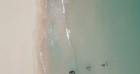 Top-down shot of white sand beach with one couple walking on the shore, aerial Stock Footage 111776280