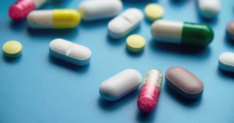 Top-Down Slide Motion of Colorful Pills on Blue Textured Surface Stock Footage 307994313