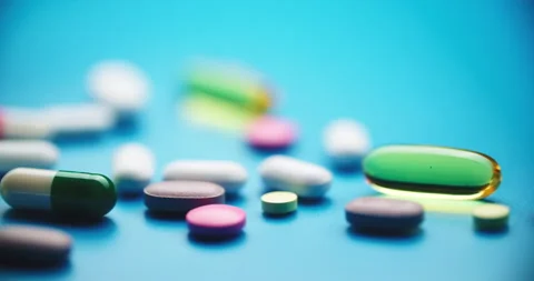 Top-Down Slide Motion of Colorful Pills on Blue Textured Surface Vídeos de archivo 307994324