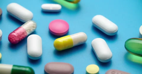 Top-Down Slide Motion of Colorful Pills on Blue Textured Surface Vídeo Stock 307996368