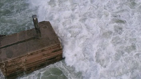 Top down slow motion drone shot of ocean waves crashing against a seawall Stock Footage 253345435