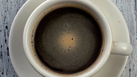 Top down slow motion shot of coffee rotating in a cup Stock Footage 98030728