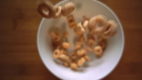 Top-down slow motion shot of cereal pieces falling through the air into a bowl Video stock 328635289