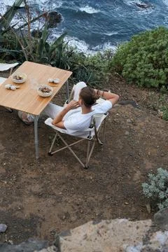 Top-Down Solitude: Unrecognizable young man Relaxing by the Ocean, Seated at a W Foto stock