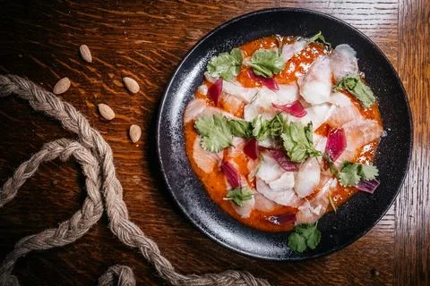 Top-down studio shot of a fish sashimi creatively arranged on a round black p Stock Photos