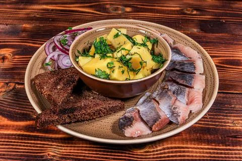Top-down studio shot of herring with boiled potatoes, rye bread, and red onio Stock Photos