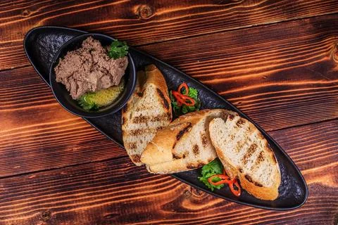 Top-down studio shot of liver pate served with toasted bread slices on a blac Stock Photos