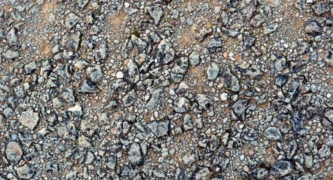 Top-down texture of coarse grey gravel, crushed stones, and dirt on a rural.. Stock Photos