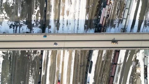 Top down timelapse aerial view of highway over snowy train yard Vidéo 333580371