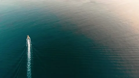 Top down tracking aerial of a medium sized speed boat sailing on murky waters to Video stock 130283396