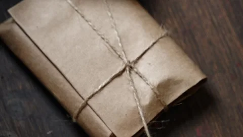 Top-Down Tying Knot on Leather Wallet Wrapped in Kraft Paper with Jute Twine Stock Footage 315528565