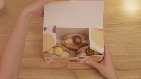 Top-down unboxing of delivery box with three filled doughnuts at home Stock Footage 321019999