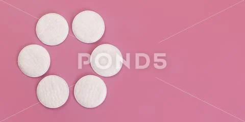 Top down view, 6 face cleaning cotton pads arranged in circle, on pink board Stock Photos