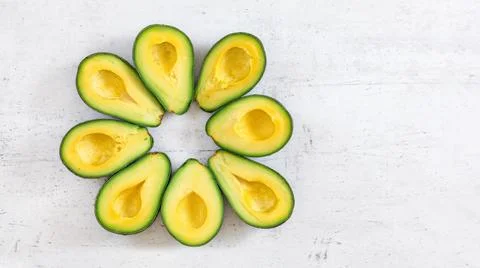 Top down view, 8 avocado halves arranged in circle on white board, banner wit Stock Photos