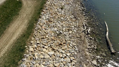 Top down view aerial video of flight above rocky bank with some driftwood. Stock Footage 129004233