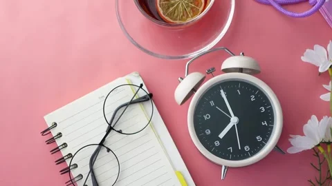 Top-down view of an alarm clock with a tea cup, notebook, and glasses on a .. Stock Footage 333031148