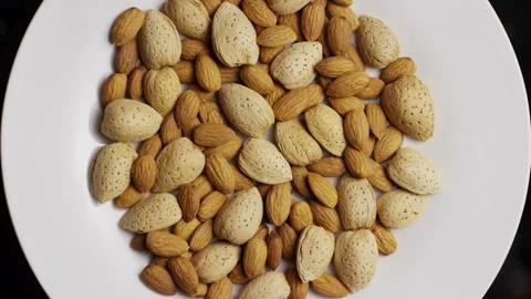 Top down view of almonds rotating on white plate Stock Footage 328135847