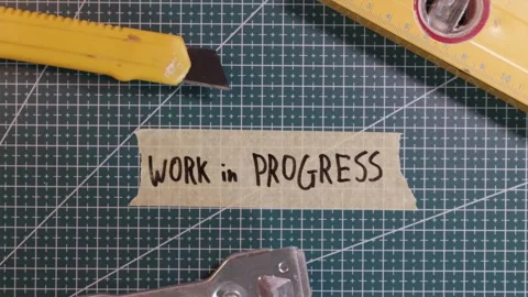 Top down view of applying WORK IN PROGRESS tape sticker on green mat. Stock-Footage 337816264