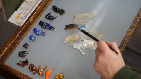 Top down view of artists palette as painter mixes paints in slow motion Stockbeeldmateriaal 104276105