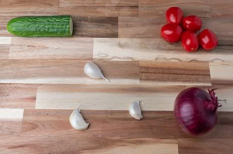 Top-down view of assorted fresh vegetables arranged on a striped wooden cutti Stock Photos